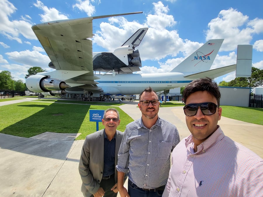 Três integrantes do grupo em frente a uma aeronave da NASA