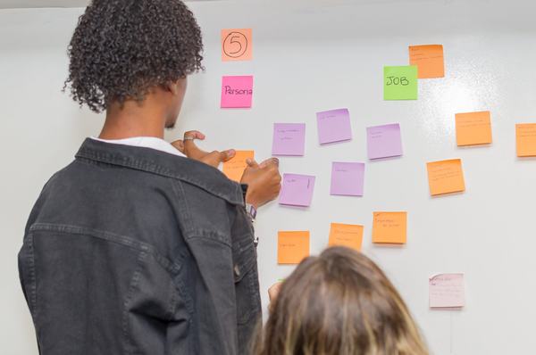 Participantes organizam ideias em post-its durante atividade de equipe