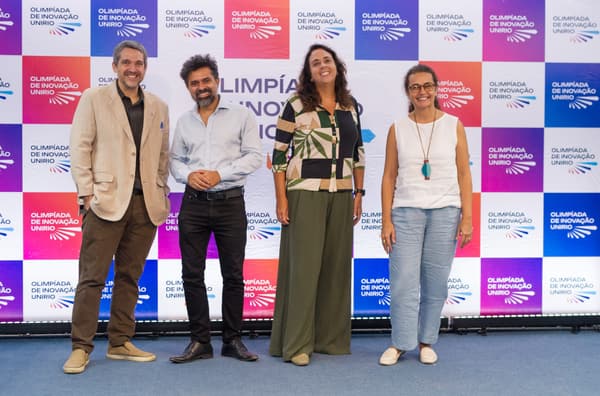 Banca avaliadora reunida diante do backdrop da Olimpíada